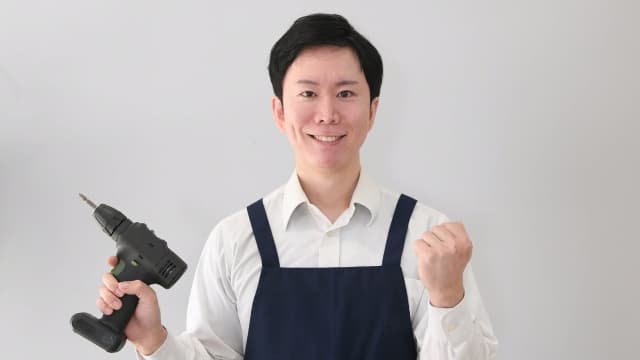 電動工具を手に、DIYで手すり取り付けをしようと意気込む男性の画像