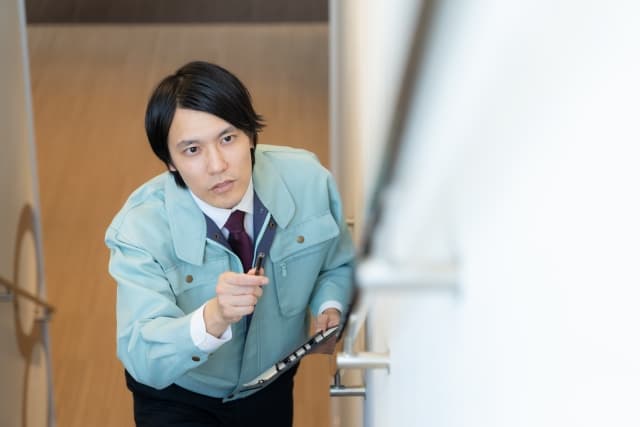 階段の手すりを確認するリフォーム会社の男性社員の写真