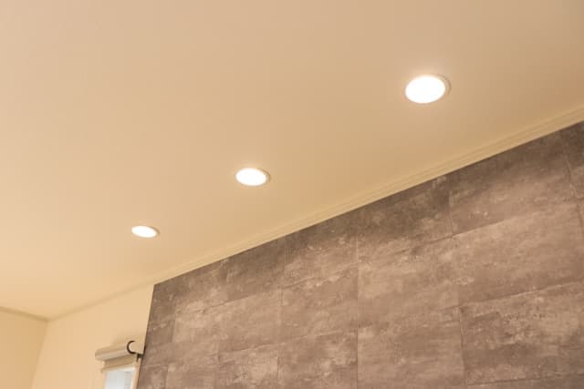 グレーのアクセントウォールと天井のダウンライトが調和したリフォーム後の照明写真