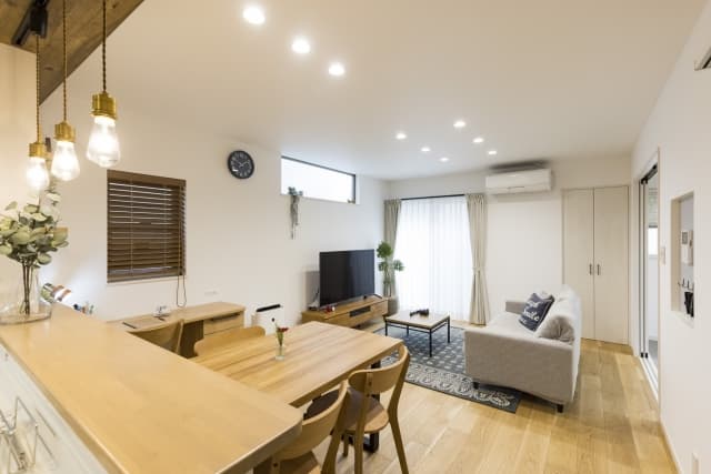 木目のテーブルとソファが並ぶリフォーム済みリビングで天井のダウンライトが空間を均一に照らす様子を写した画像