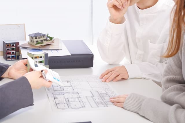 クロス張り替えの費用相場について、間取り図と電卓を用いて見積もり相談を行う様子