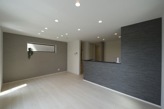 グレーのアクセントクロスを採用したモダンで清潔感のあるリビングの壁紙リフォームの事例