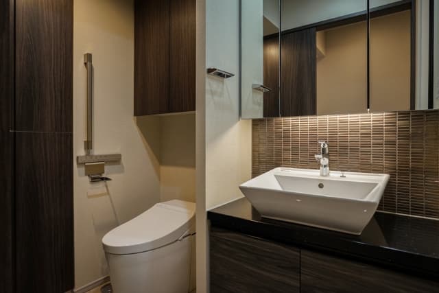 ダークブラウンの木目調とタイルを組み合わせた、ホテルライクでスタイリッシュなトイレと洗面スペースの内装事例。