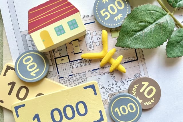 壁紙リフォームの予算や費用目安を示す、住宅模型とおもちゃのお金を置いた間取り