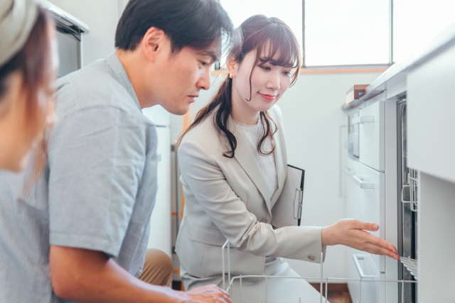 さいたま市のキッチンリフォーム相談|ショールームでビルトイン食洗機の説明を受けるご夫婦と担当者
