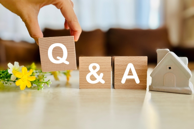 「Q&A」の木製ブロックを置く手と白い家のオブジェ。エコカラットの費用や追加工事に関するよくある質問のイメージ画像