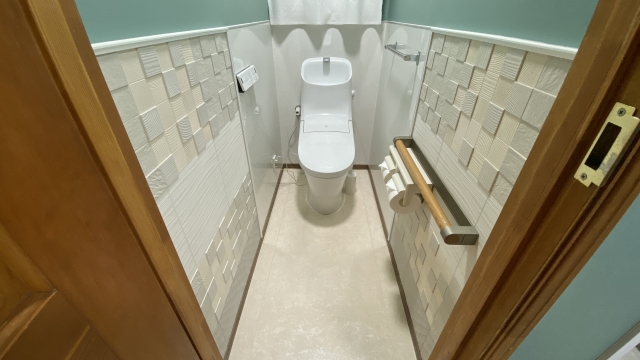 エコカラットプラスを壁に貼った、おしゃれで清潔なトイレの施工事例。市松模様のデザインタイルとミントグリーンの壁が特徴で、ホテルライクな雰囲気を演出している。